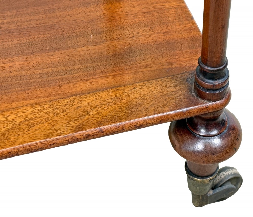 A three-tier Regency mahogany whatnot featuring a pierced brass gallery top rail, turned support columns, and brass castors. View XII
