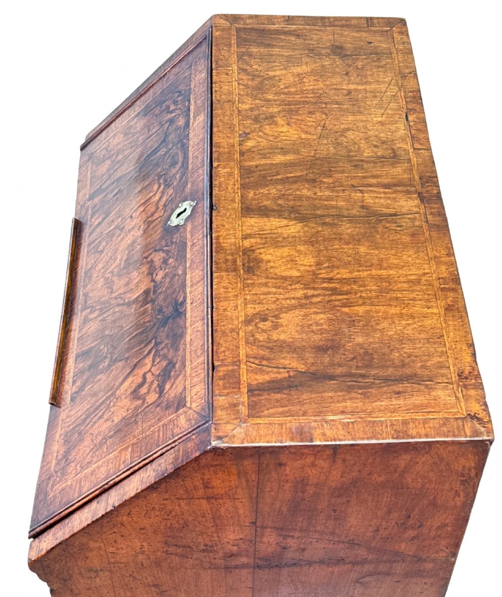 An early 18th-century walnut bureau on legs featuring a slant-front lid, small drawers with brass teardrop handles, and cabriole legs. View VI