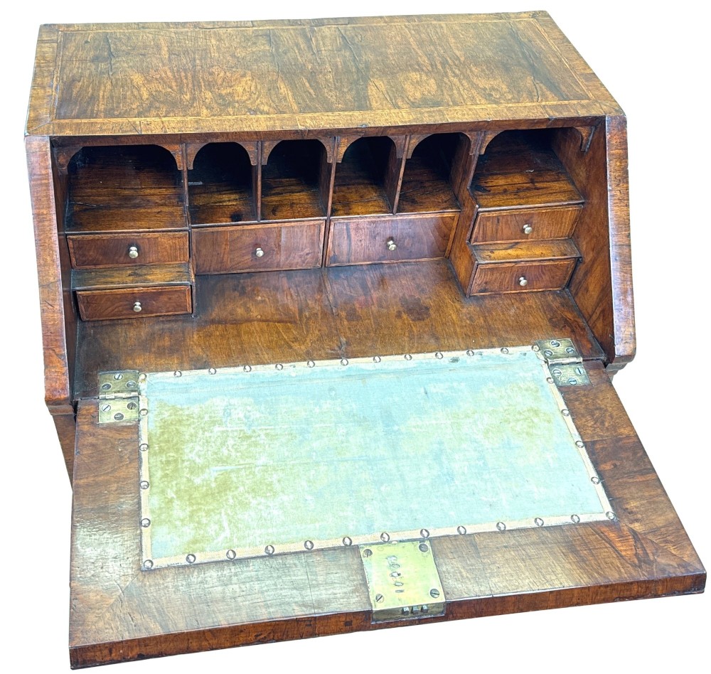 An early 18th-century walnut bureau on legs featuring a slant-front lid, small drawers with brass teardrop handles, and cabriole legs. View VII