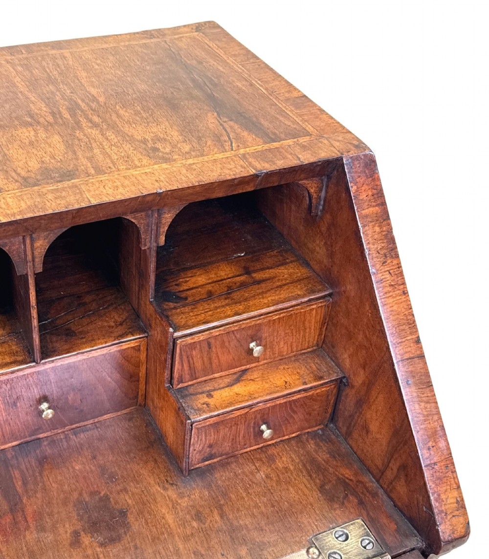 An early 18th-century walnut bureau on legs featuring a slant-front lid, small drawers with brass teardrop handles, and cabriole legs. View IX