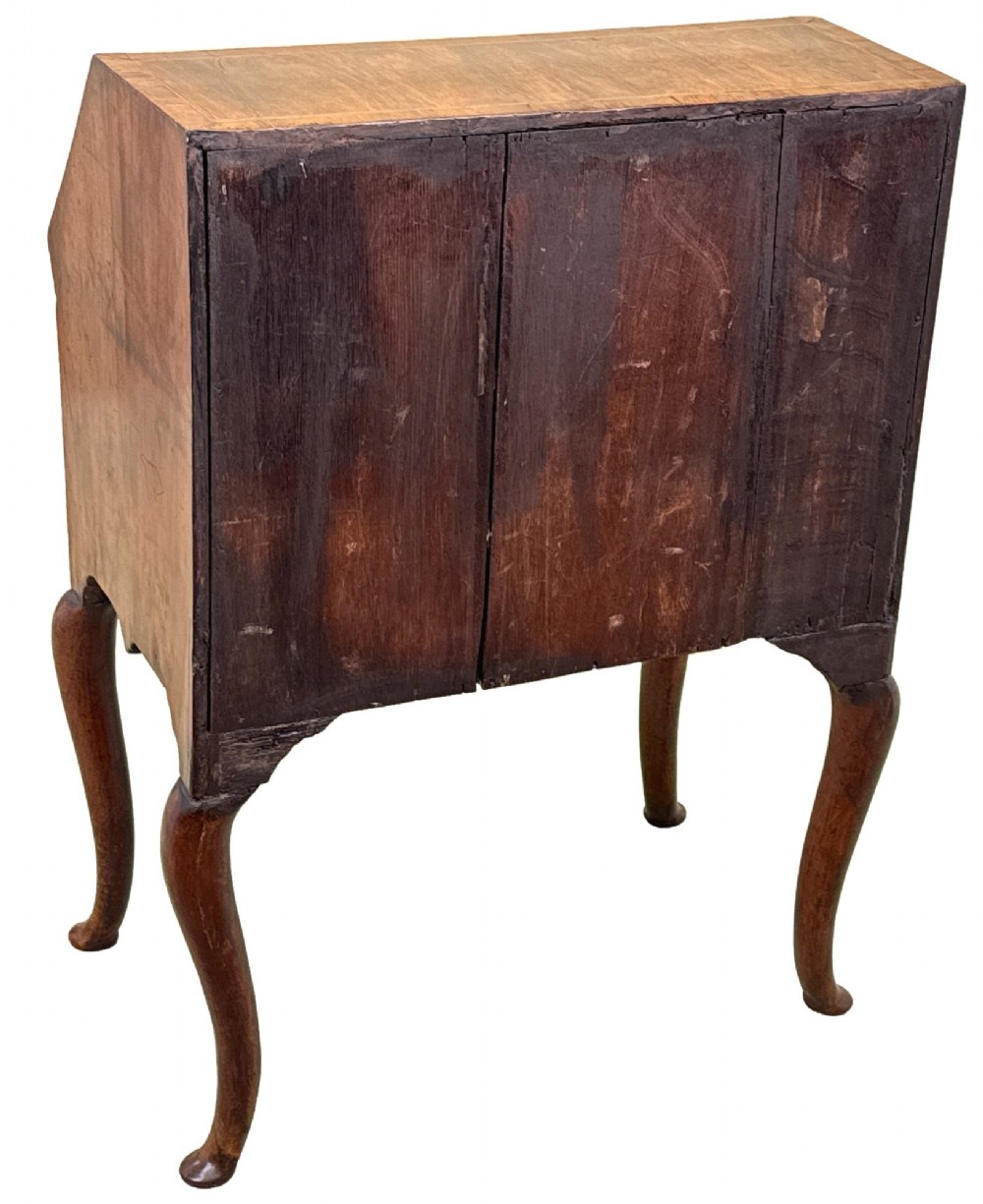 An early 18th-century walnut bureau on legs featuring a slant-front lid, small drawers with brass teardrop handles, and cabriole legs. View XIV