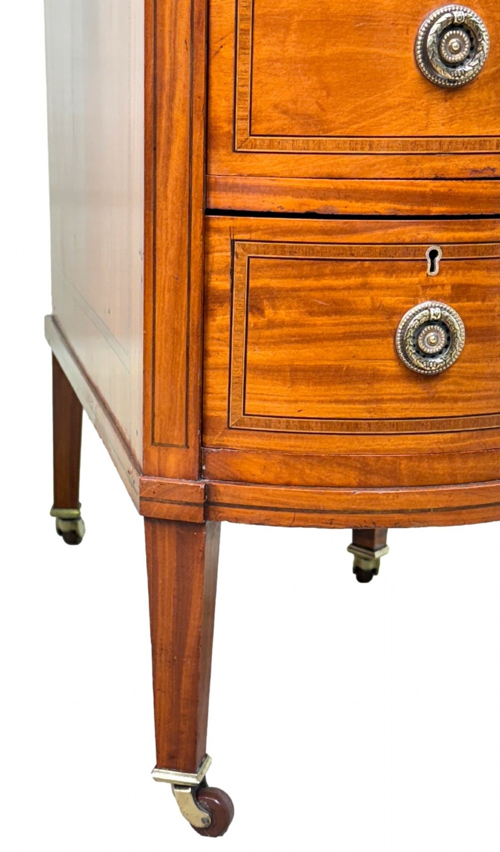 A 19th-century kidney-shaped satinwood writing desk featuring an inset green leather top, nine inlaid drawers with brass ring handles, and tapered square legs on castors. View IV