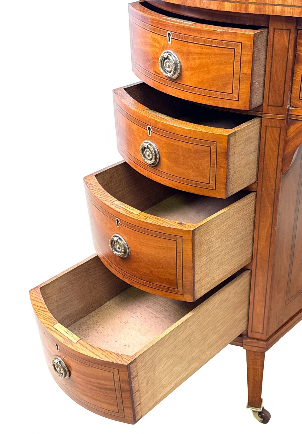 A 19th-century kidney-shaped satinwood writing desk featuring an inset green leather top, nine inlaid drawers with brass ring handles, and tapered square legs on castors. View V