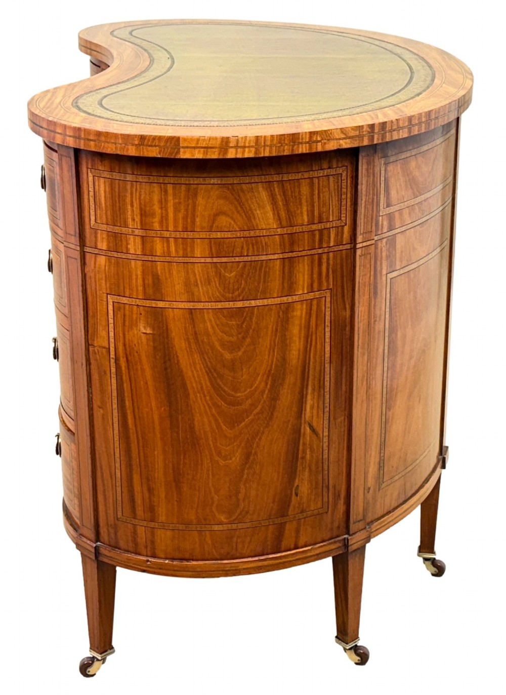 A 19th-century kidney-shaped satinwood writing desk featuring an inset green leather top, nine inlaid drawers with brass ring handles, and tapered square legs on castors. View VI