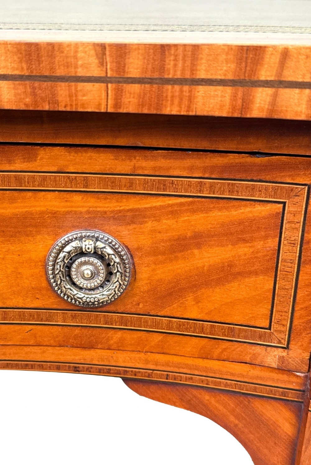 A 19th-century kidney-shaped satinwood writing desk featuring an inset green leather top, nine inlaid drawers with brass ring handles, and tapered square legs on castors. View VII