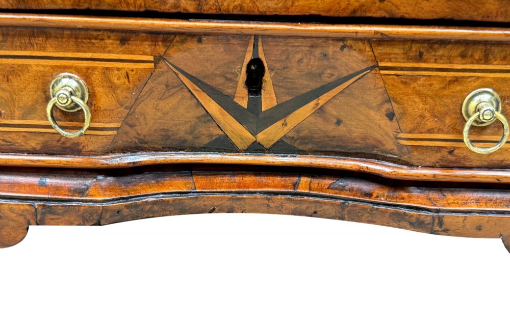 An early 18th-century walnut miniature chest featuring two drawers, star marquetry inlay, crossbanding, brass drop ring handles, and bracket feet. View IV