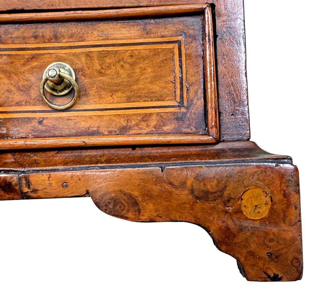 An early 18th-century walnut miniature chest featuring two drawers, star marquetry inlay, crossbanding, brass drop ring handles, and bracket feet. View IX
