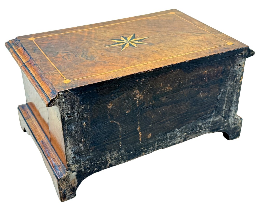 An early 18th-century walnut miniature chest featuring two drawers, star marquetry inlay, crossbanding, brass drop ring handles, and bracket feet. View XI