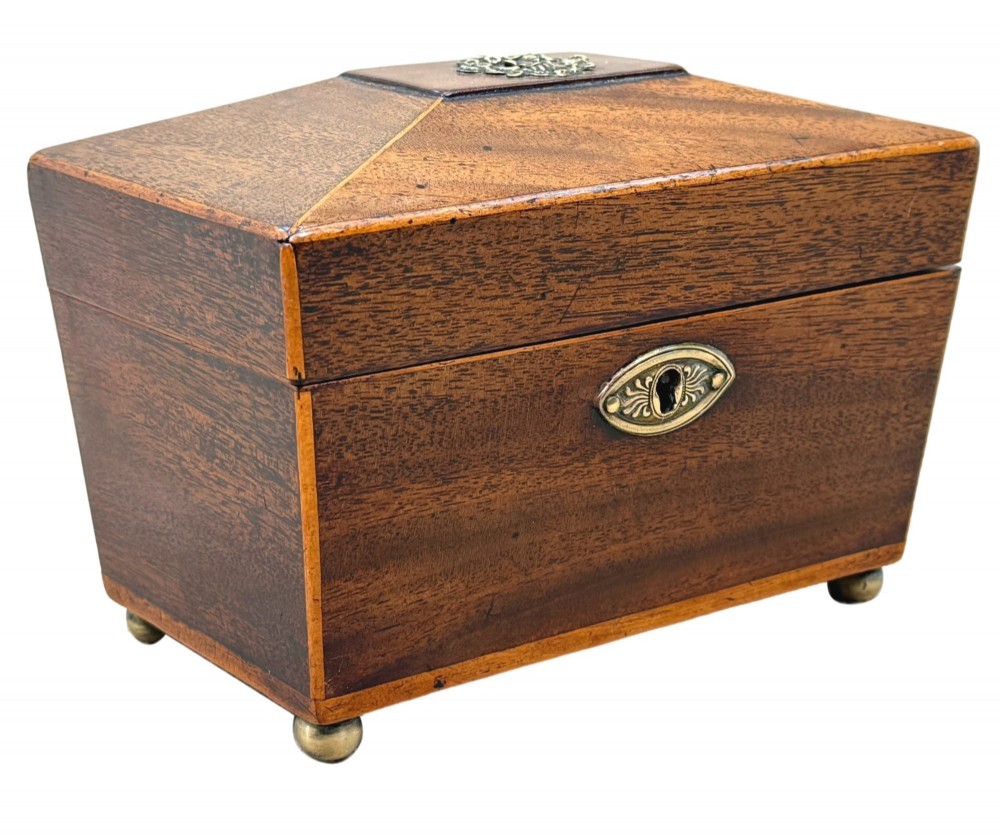 An eighteenth-century Georgian mahogany tea caddy featuring a sarcophagus shape, boxwood edging, an oval brass escutcheon, and brass ball feet. View VIII