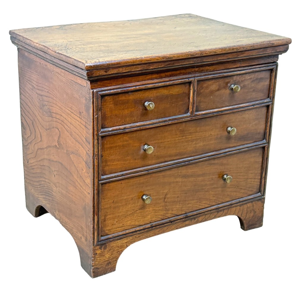 An 18th-century warm brown elm close stool designed as a small Georgian chest of drawers with bracket feet and brass handles. View X