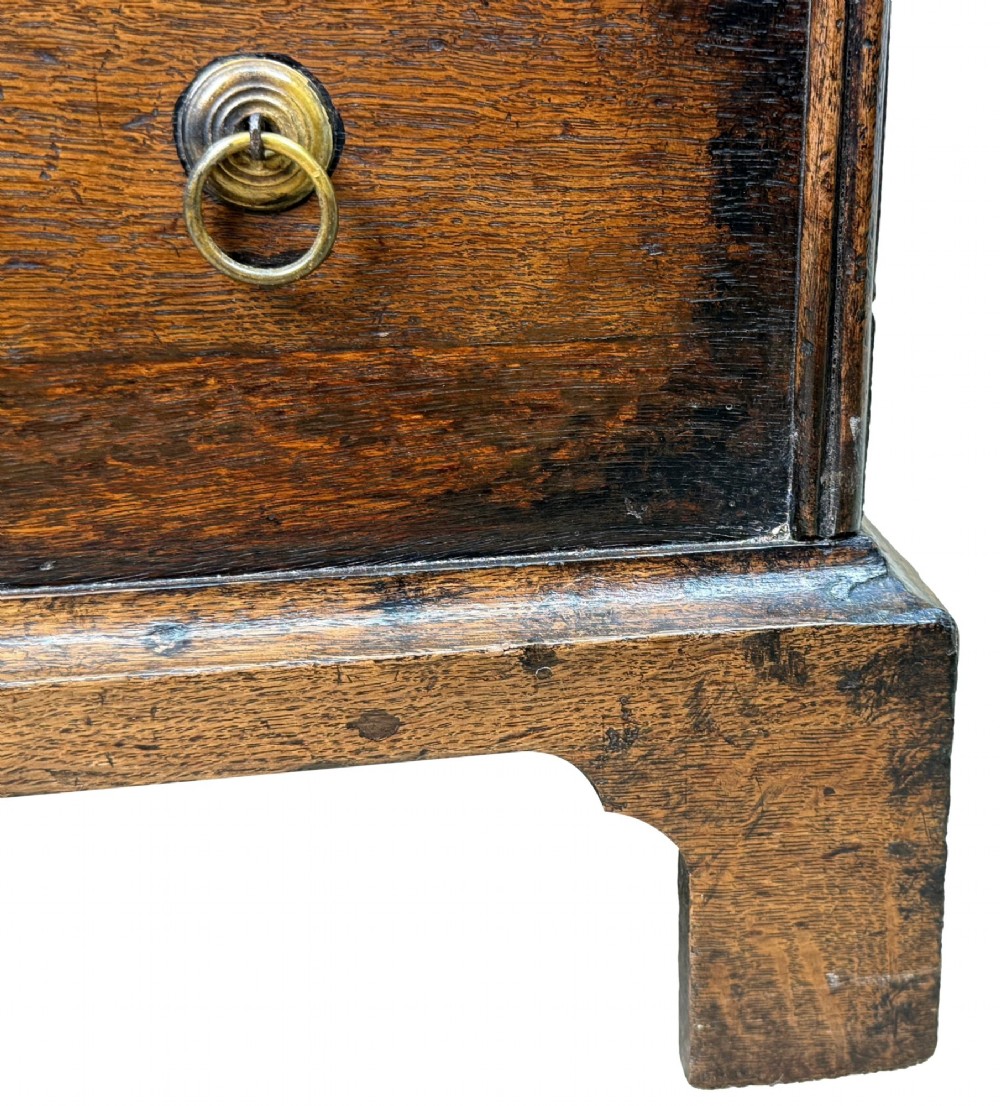 An 18th-century dark oak close stool designed as a small chest with faux drawer fronts, brass ring handles, and bracket feet. View VI