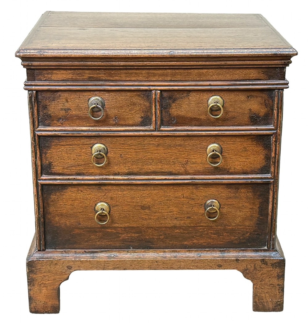 An 18th-century dark oak close stool designed as a small chest with faux drawer fronts, brass ring handles, and bracket feet. View X