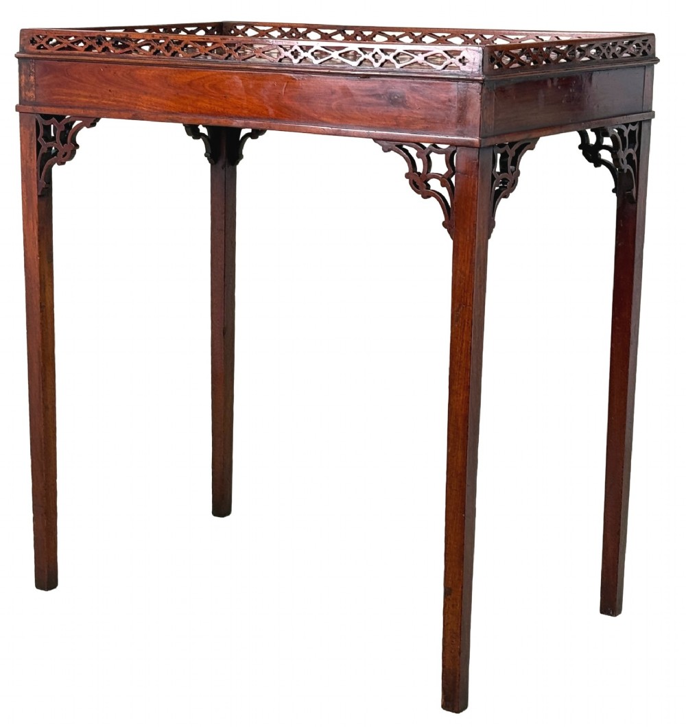 A rectangular dark mahogany silver table featuring a pierced fretwork gallery top, carved corner spandrels, and four straight legs.