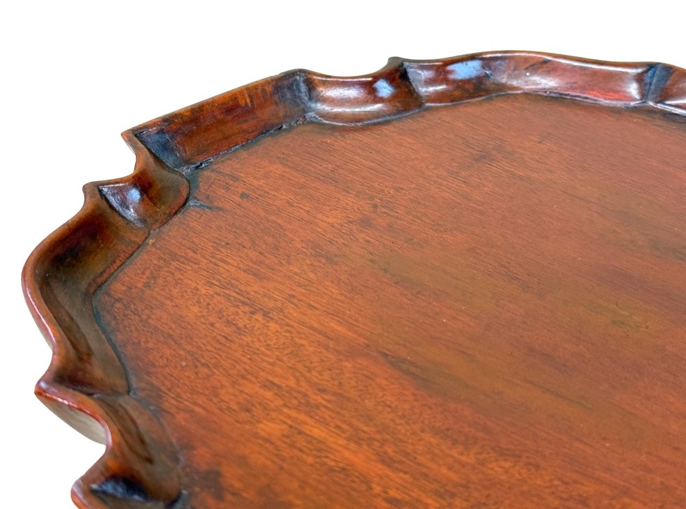 An 18th-century mahogany kettle stand with a raised piecrust top on a turned pedestal column and tripod base. View II
