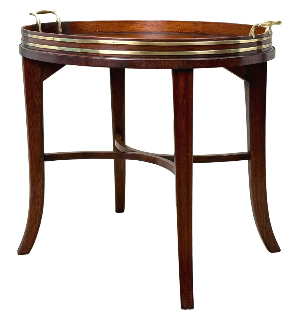 A Georgian mahogany oval tray table featuring a double brass-bound gallery rim, twin side handles, and four splayed legs joined by an X-frame stretcher.