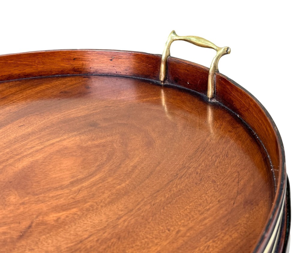 A Georgian mahogany oval tray table featuring a double brass-bound gallery rim, twin side handles, and four splayed legs joined by an X-frame stretcher. View V