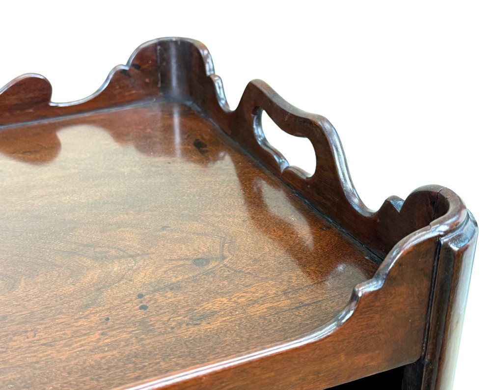 An 18th-century Georgian mahogany bedside table with a wavy gallery top featuring pierced hand cutouts, an open shelf compartment, and four square legs. View IX