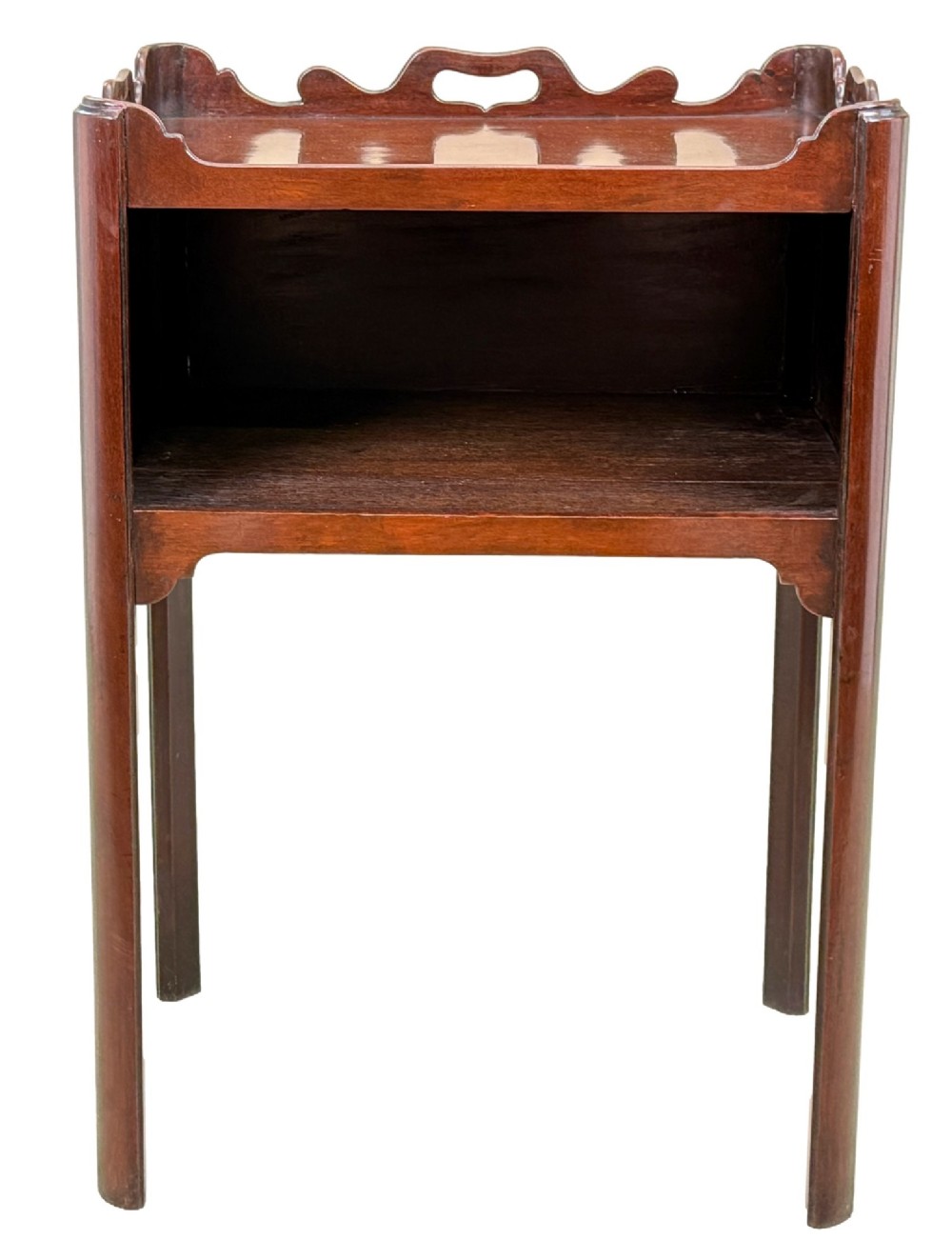 An 18th-century Georgian mahogany bedside table with a wavy gallery top featuring pierced hand cutouts, an open shelf compartment, and four square legs. View X