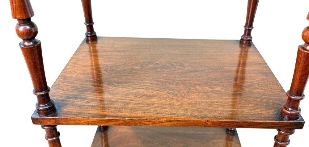 A mid-19th-century rosewood three-tier whatnot with turned spindles, finials, and brass castors. View VI