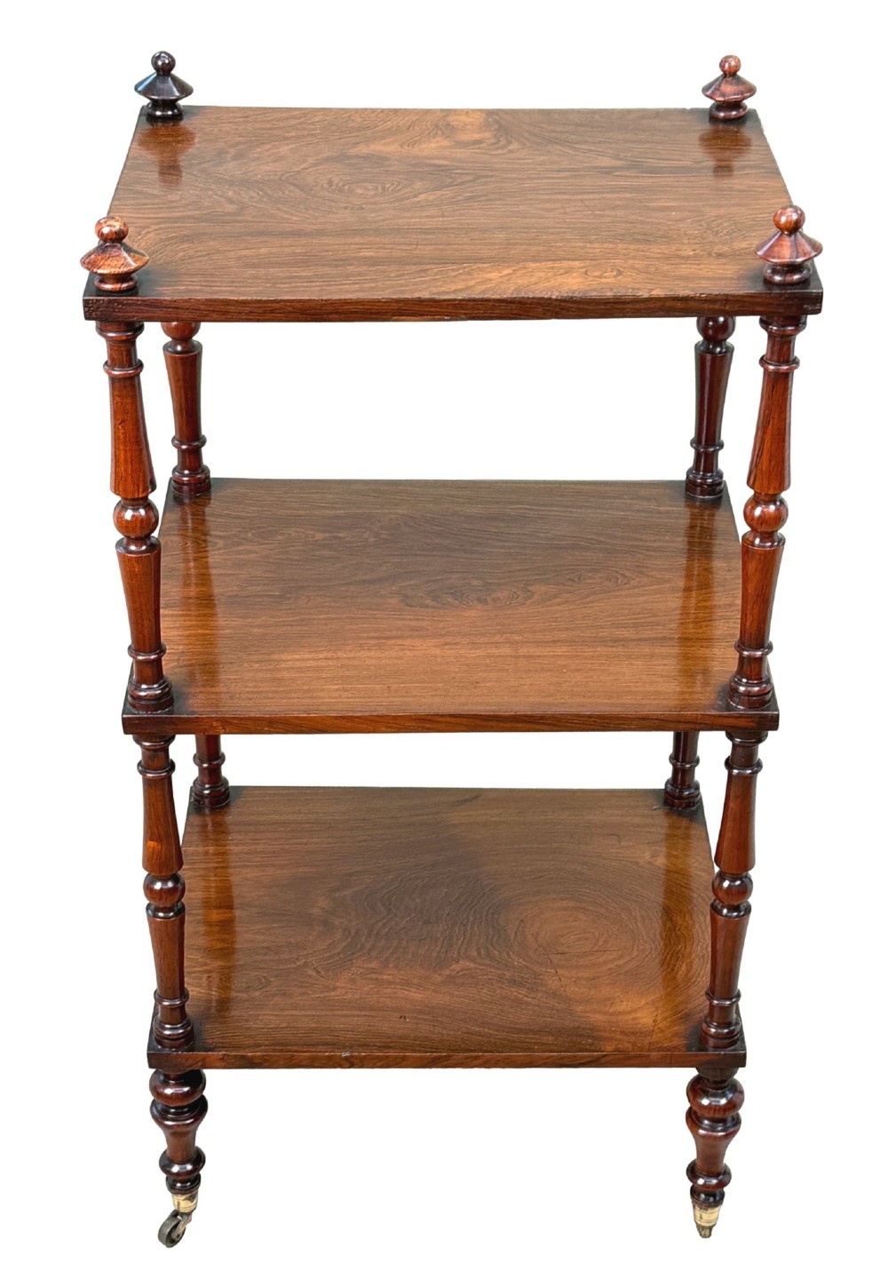 A mid-19th-century rosewood three-tier whatnot with turned spindles, finials, and brass castors. View VII