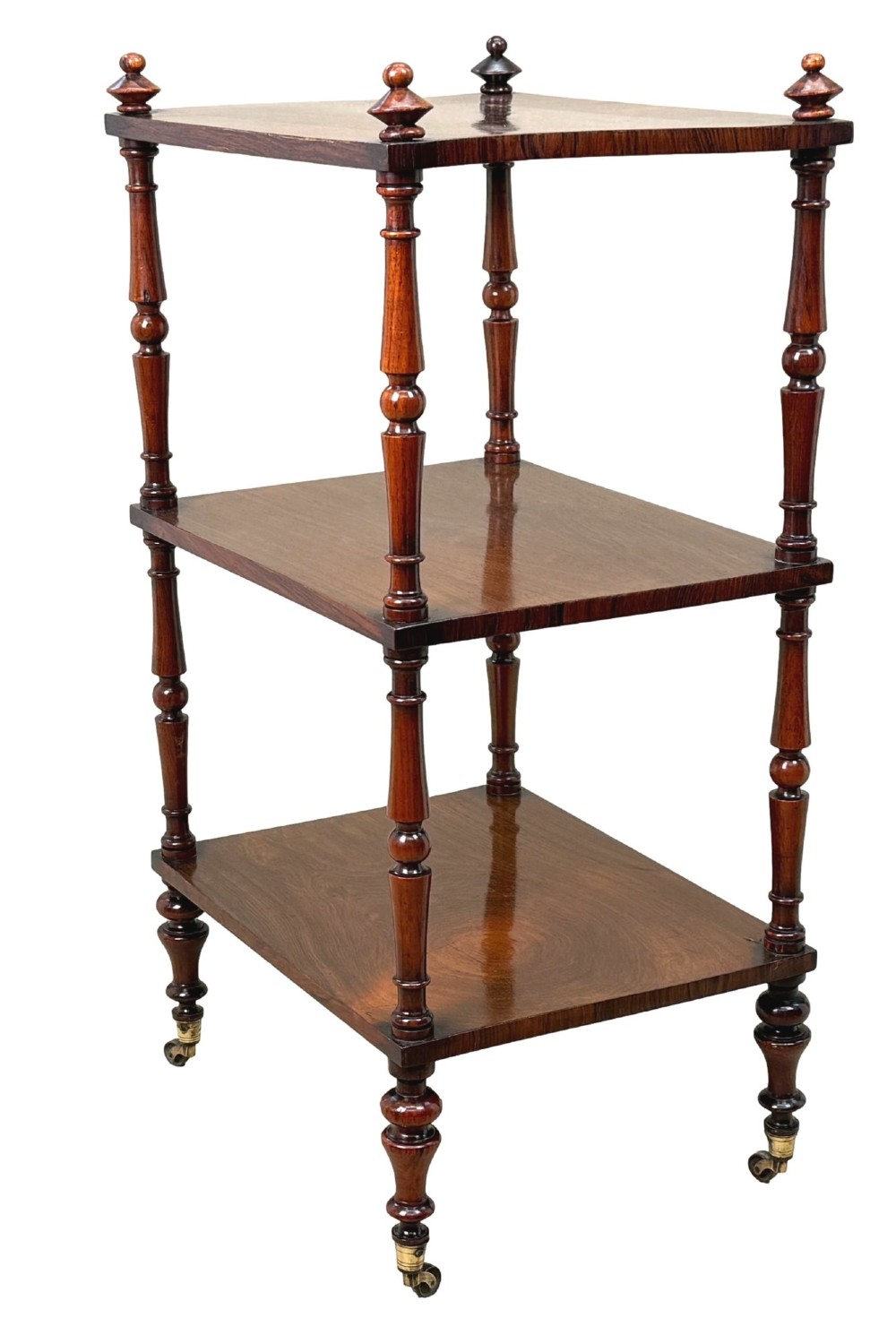 A mid-19th-century rosewood three-tier whatnot with turned spindles, finials, and brass castors. View IX