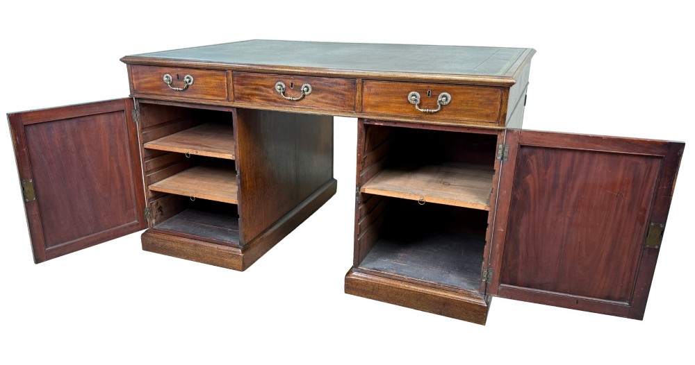 An 18th-century Georgian mahogany partners desk featuring three top frieze drawers and twin pedestal cupboards set on a plinth base. View II