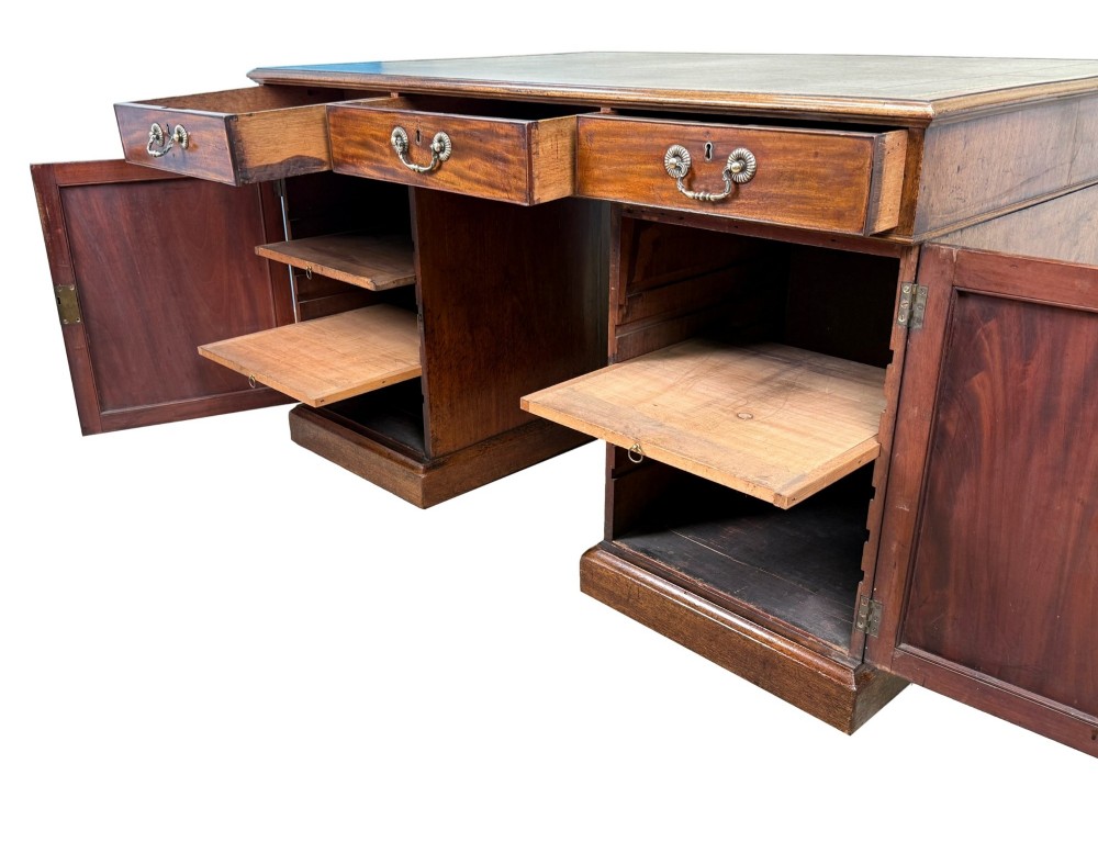 An 18th-century Georgian mahogany partners desk featuring three top frieze drawers and twin pedestal cupboards set on a plinth base. View VI