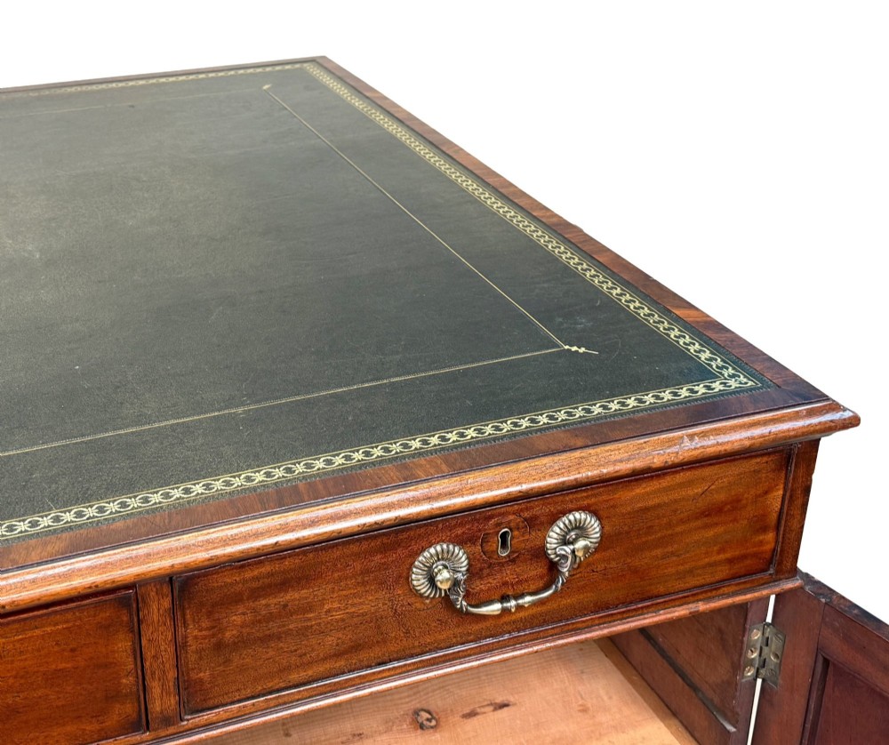 An 18th-century Georgian mahogany partners desk featuring three top frieze drawers and twin pedestal cupboards set on a plinth base. View X