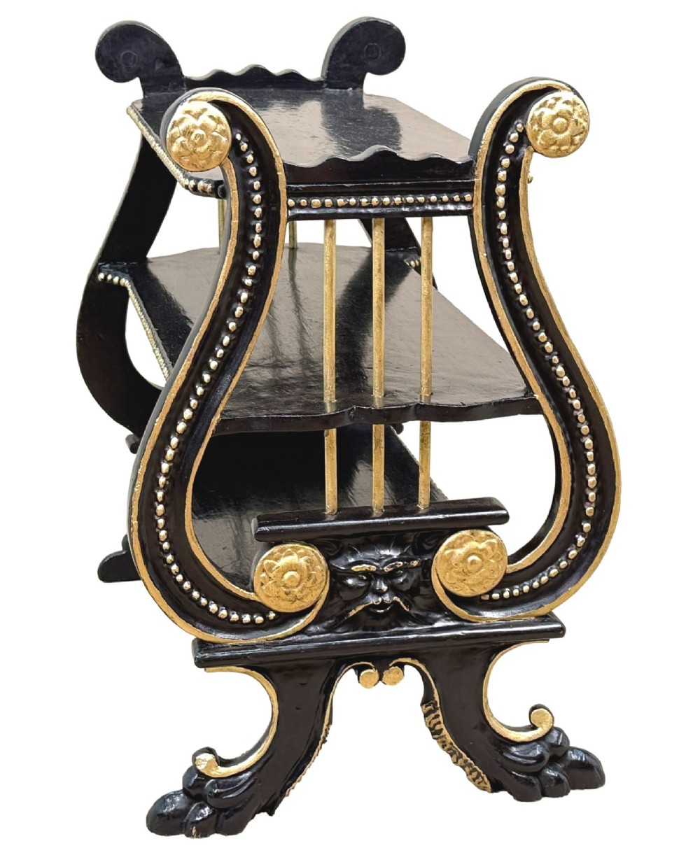 A late nineteenth-century ebonised three-tiered etagere featuring lyre-shaped side supports, gilt bead trim along the shelf edges, and carved scroll feet. View II