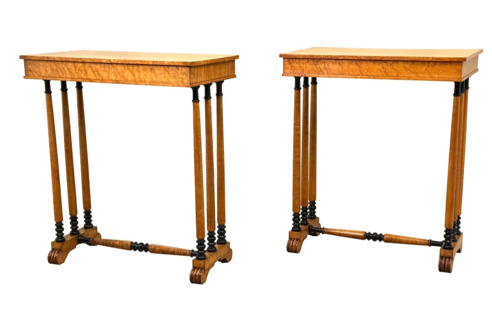 A pair of Regency birdseye maple occasional tables featuring quadrupled slender turned legs with ebonised details and a stretcher base.