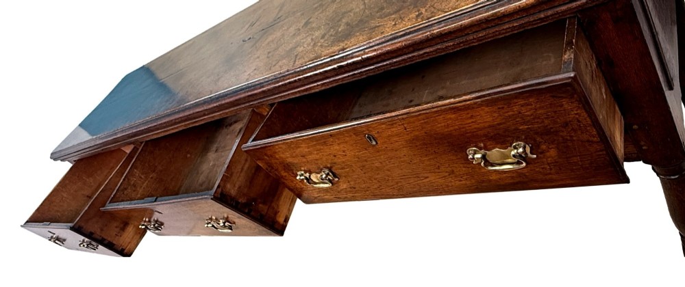 An early eighteenth-century oak dresser base featuring three drawers with brass drop handles, brass keyhole escutcheons, turned front legs, and a dark brown finish. View V