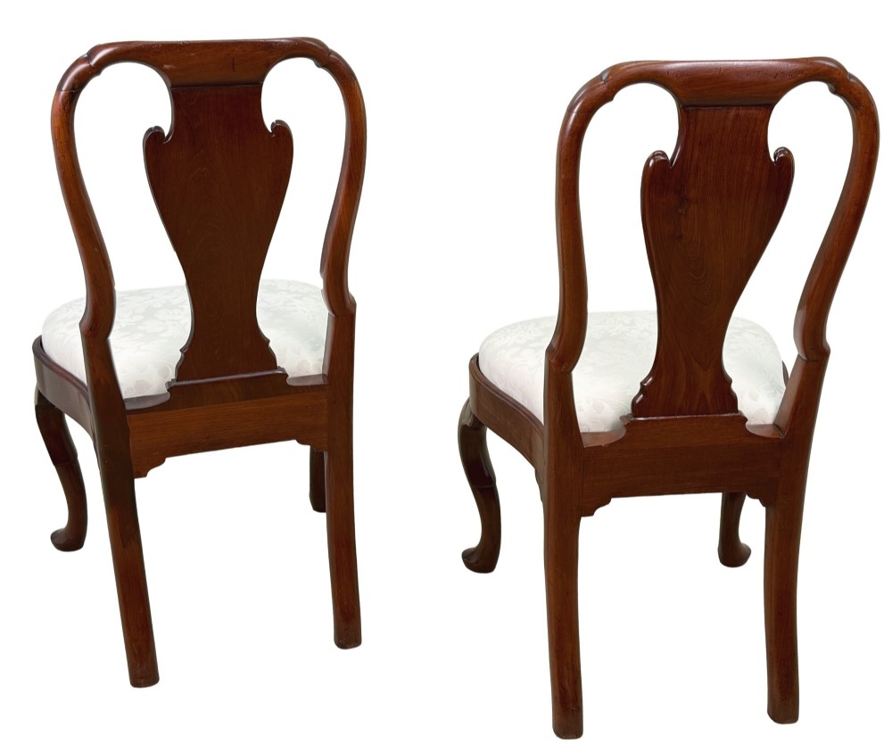 A pair of early 18th-century Queen Anne walnut side chairs featuring vase-shaped back splats, curved cabriole front legs, and cream upholstered drop-in seats. View VI