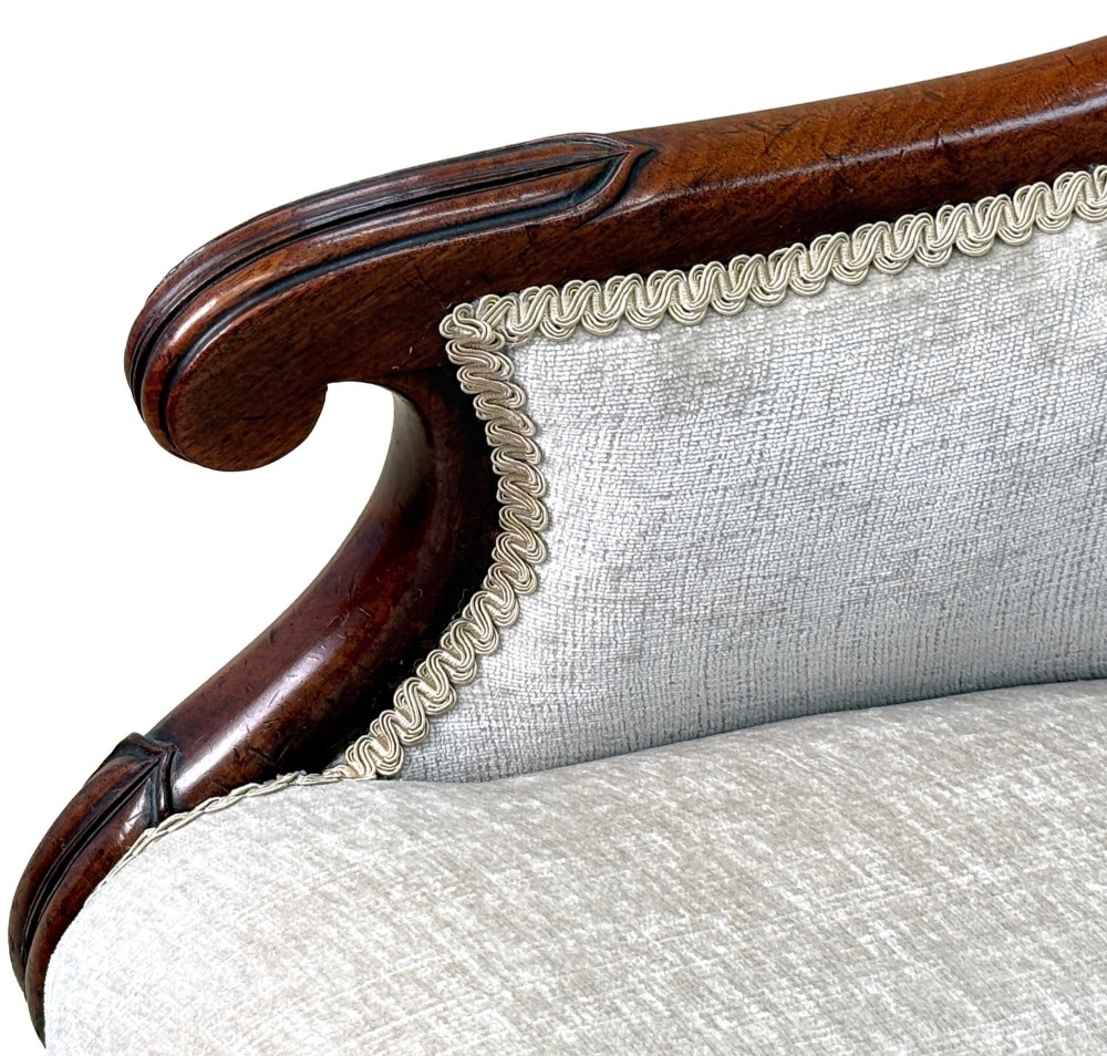 A 19th-century English Regency mahogany tub armchair with cream upholstery, scrolled armrests, turned legs, and brass castors. View IV