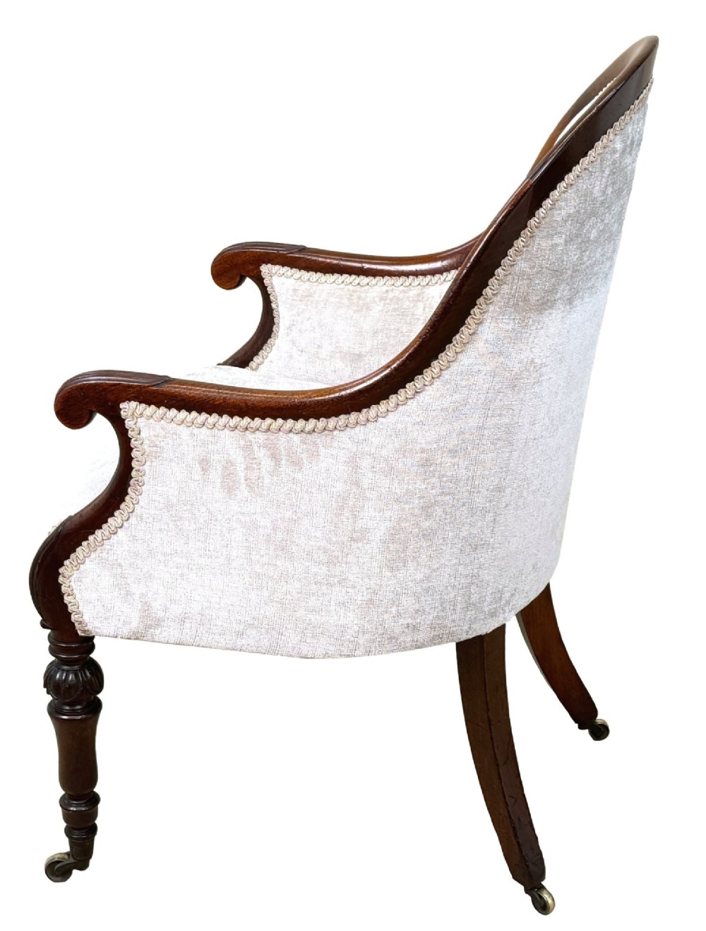 A 19th-century English Regency mahogany tub armchair with cream upholstery, scrolled armrests, turned legs, and brass castors. View V