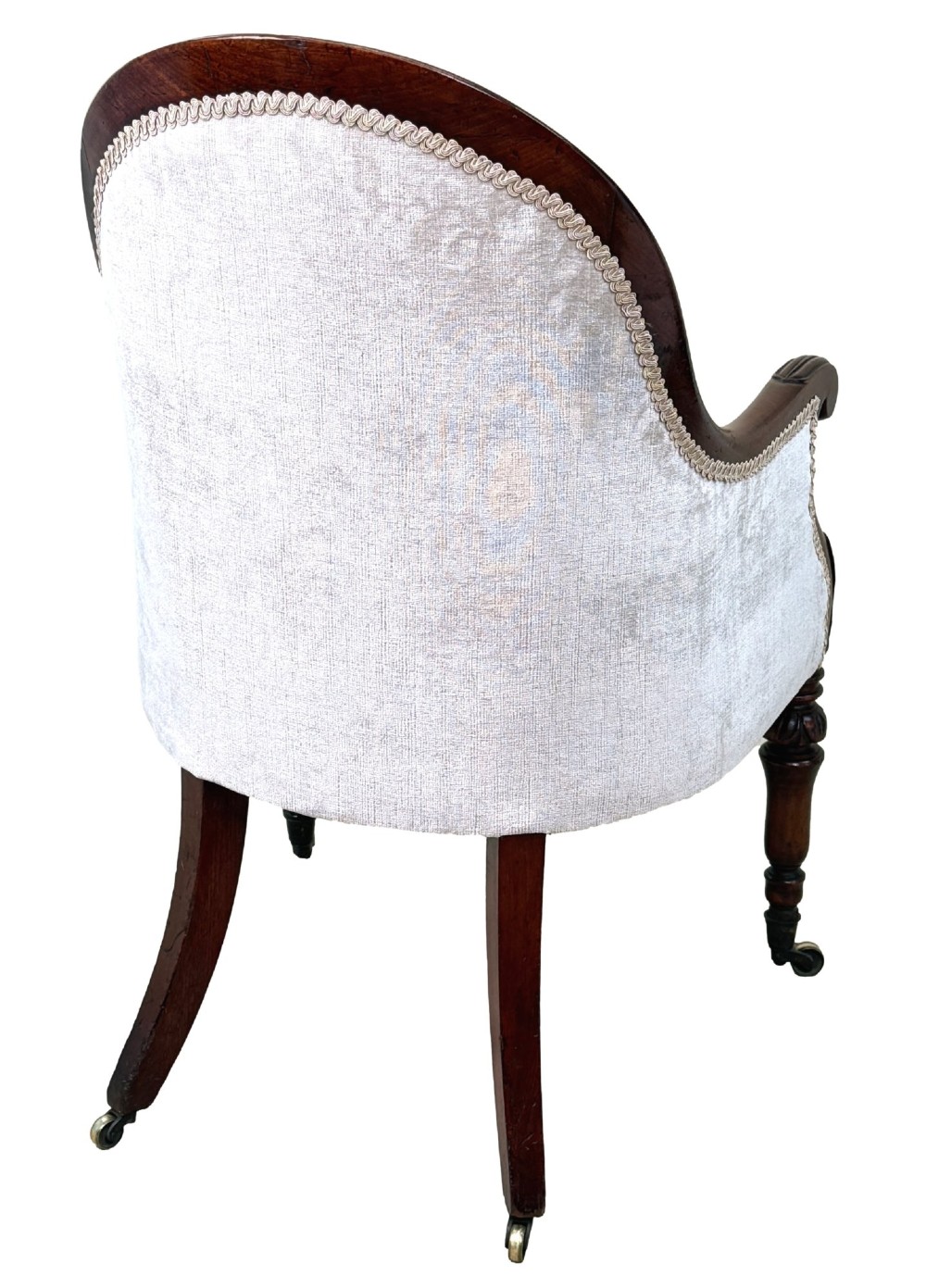 A 19th-century English Regency mahogany tub armchair with cream upholstery, scrolled armrests, turned legs, and brass castors. View VII