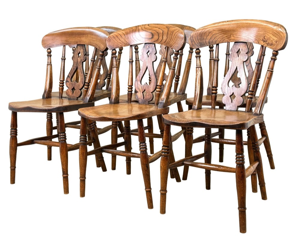 A set of six Victorian wooden Windsor dining chairs featuring shaped crest rails, pierced back splats, contoured saddle seats, and turned legs.