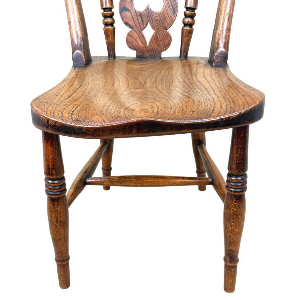 A set of six Victorian wooden Windsor dining chairs featuring shaped crest rails, pierced back splats, contoured saddle seats, and turned legs. View IV