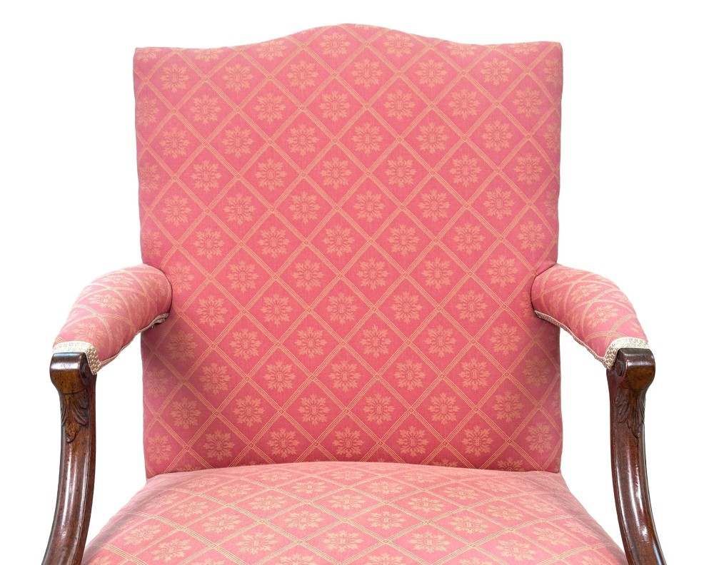 An 18th-century Georgian mahogany Gainsborough armchair with red patterned upholstery, curved carved arm supports, an H-stretcher frame, and brass castors. View IX