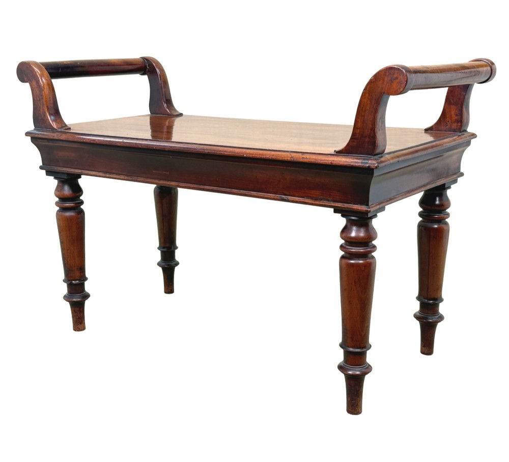 A mid-19th-century mahogany window seat with turned legs, a flat wooden seat, and curved end handles.