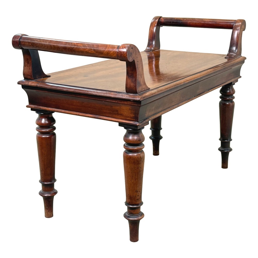 A mid-19th-century mahogany window seat with turned legs, a flat wooden seat, and curved end handles. View II