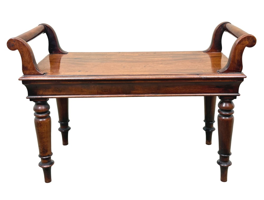 A mid-19th-century mahogany window seat with turned legs, a flat wooden seat, and curved end handles. View V