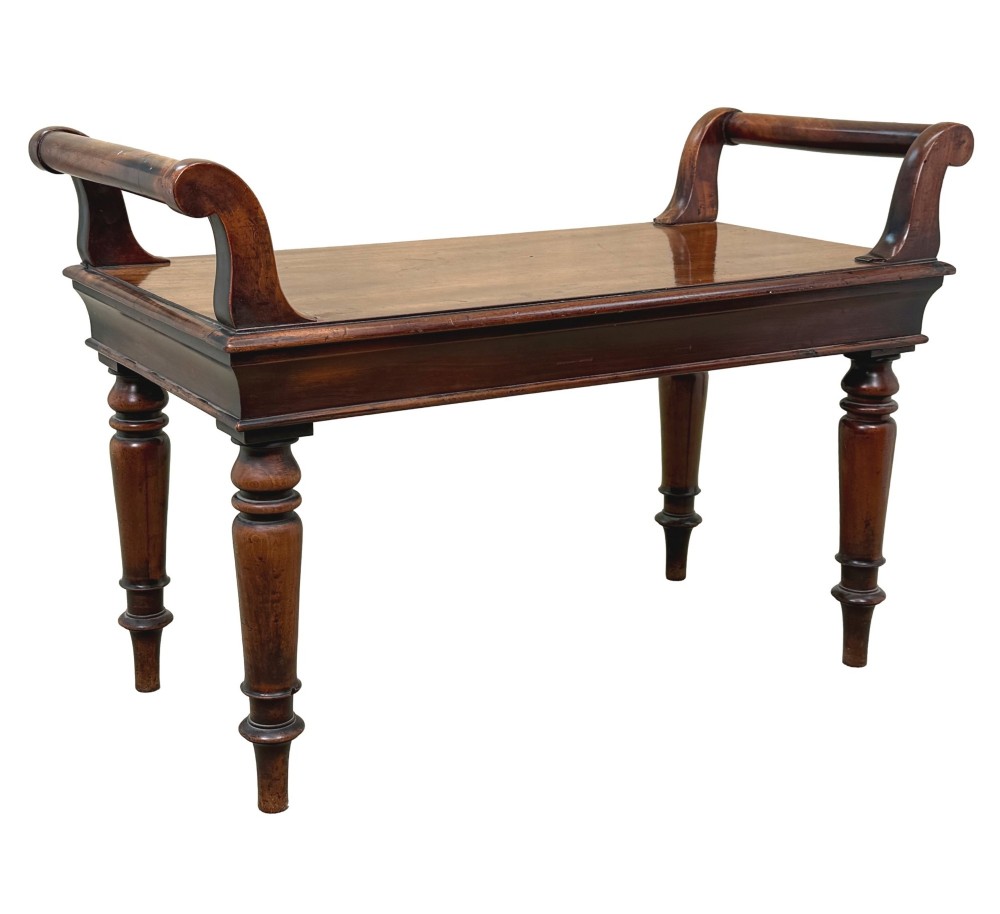 A mid-19th-century mahogany window seat with turned legs, a flat wooden seat, and curved end handles. View IX