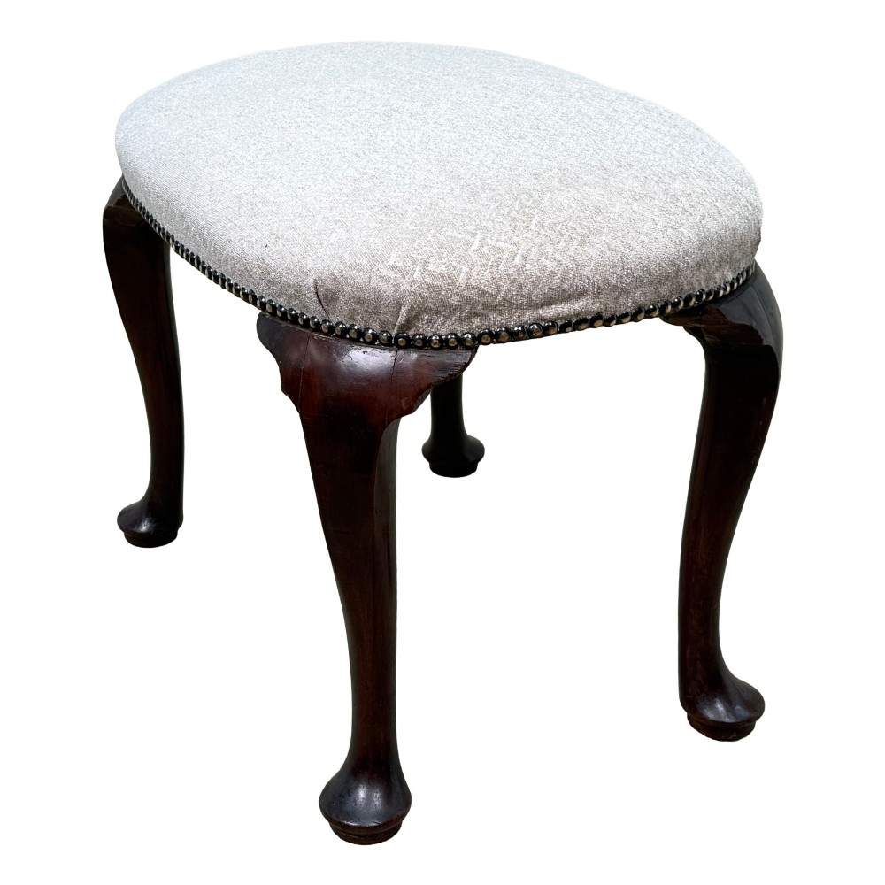 An early 18th-century George I walnut stool featuring an oval light grey upholstered seat trimmed with metal studs above four cabriole legs ending in pad feet. View II