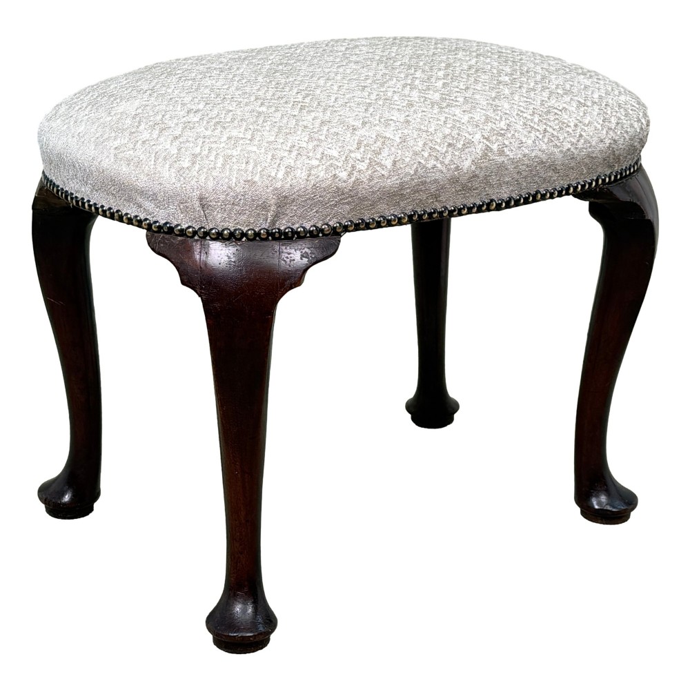 An early 18th-century George I walnut stool featuring an oval light grey upholstered seat trimmed with metal studs above four cabriole legs ending in pad feet. View VIII