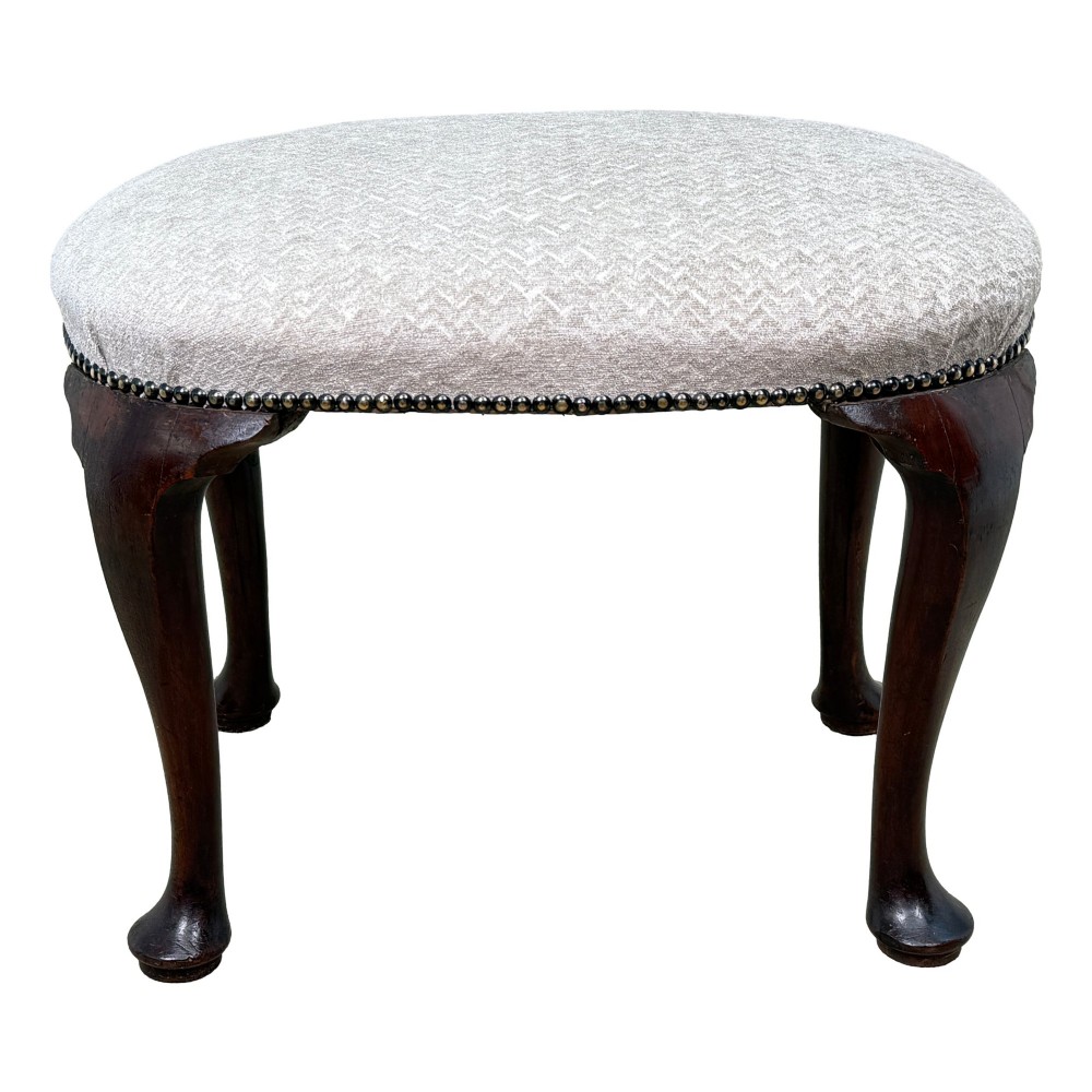 An early 18th-century George I walnut stool featuring an oval light grey upholstered seat trimmed with metal studs above four cabriole legs ending in pad feet. View XI