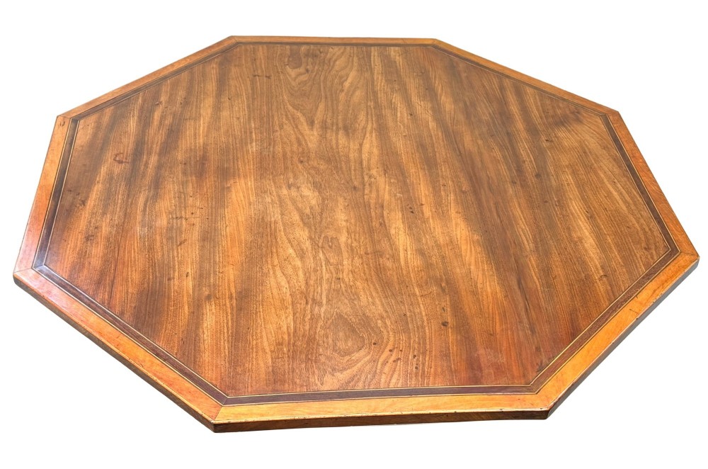 An 18th-century Georgian mahogany octagonal centre table with inlaid crossbanding, a central pedestal column, and tripod legs on brass castors. View V