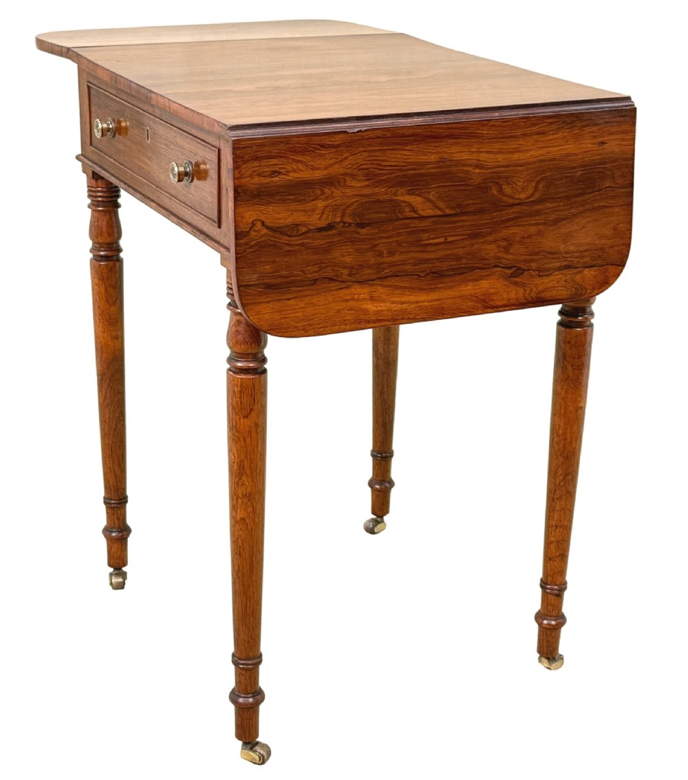 An early 19th-century Regency rosewood Pembroke table featuring extended drop leaves, turned legs on brass castors, and a single frieze drawer with brass knobs. View VI