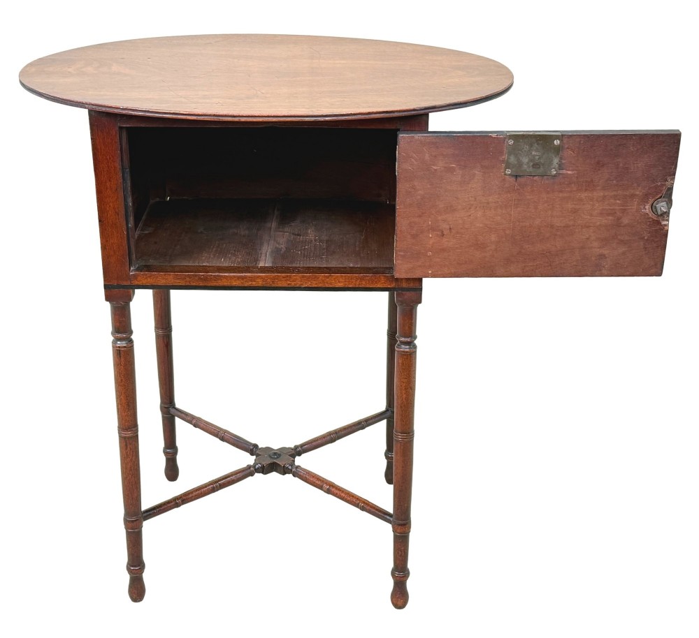 An early 19th-century Georgian mahogany side table featuring an oval top, single door cupboard with brass knob, turned legs, and an X-shaped cross stretcher. View II