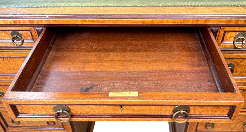 A mid-19th-century English birdseye maple pedestal desk featuring a green leather writing surface, multiple drawers with brass ring drop handles, and a plinth base. View II