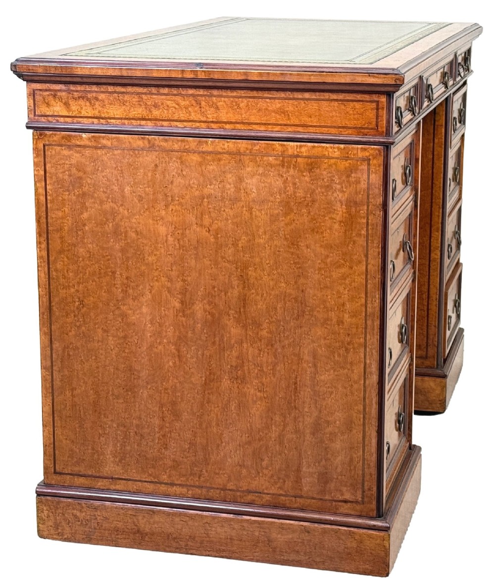A mid-19th-century English birdseye maple pedestal desk featuring a green leather writing surface, multiple drawers with brass ring drop handles, and a plinth base. View III